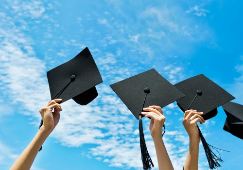 Geslaagden steken hoedjes/diploma in de lucht