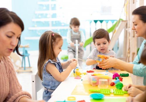 Spelende kinderen met begeleiders in kinderopvang