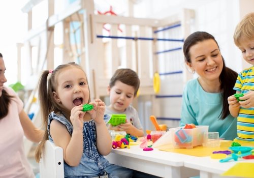 Spelende kinderen met begeleiders in kinderopvang