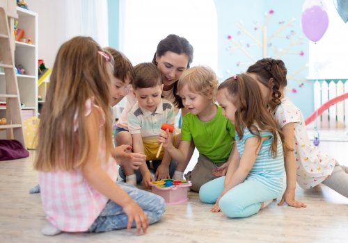 Spelende kinderen met begeleider in kinderopvang