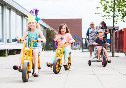 Kinderopvang met fietsende kinderen en pedagogisch medewerkers