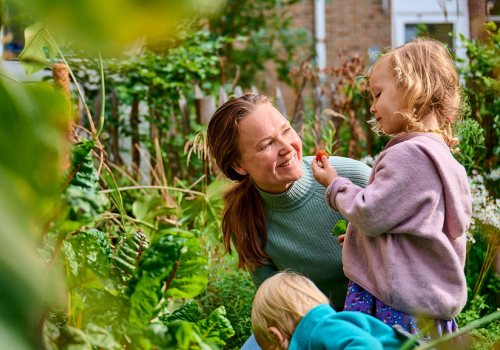 Pedagogisch medewerker kijkt lachend naar peuter