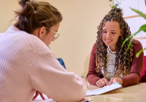 Twee vrouwen aan tafel bespreken een document
