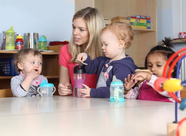 Pedagogisch professional aan een tafel met spelende kinderen