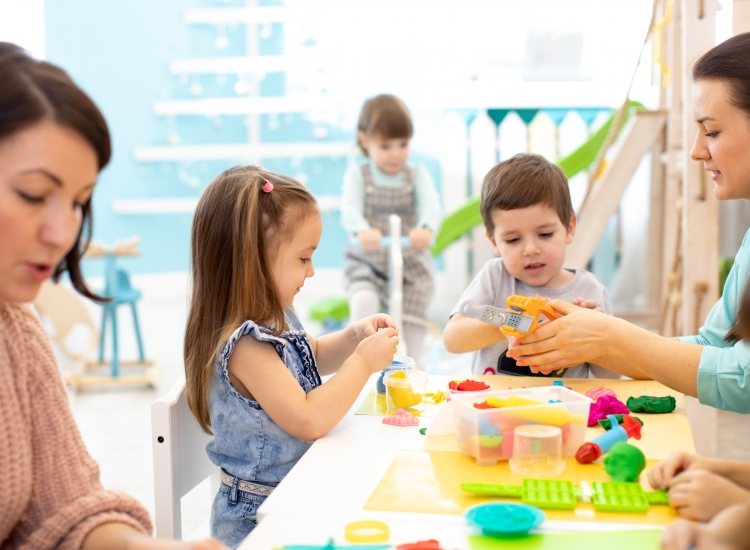 Spelende kinderen met begeleiders in kinderopvang