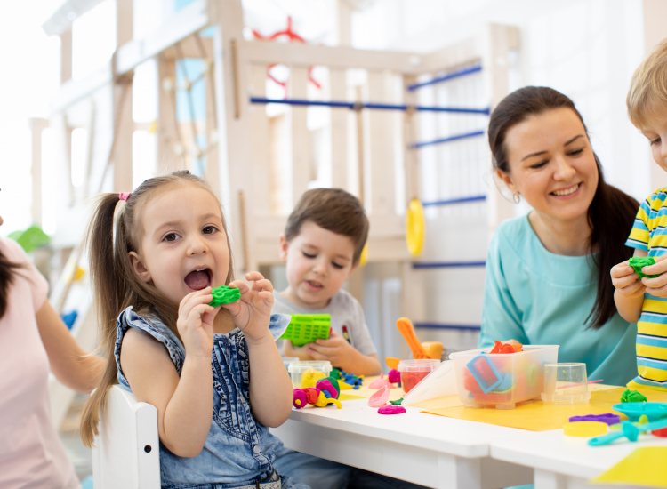 Spelende kinderen met begeleiders in kinderopvang