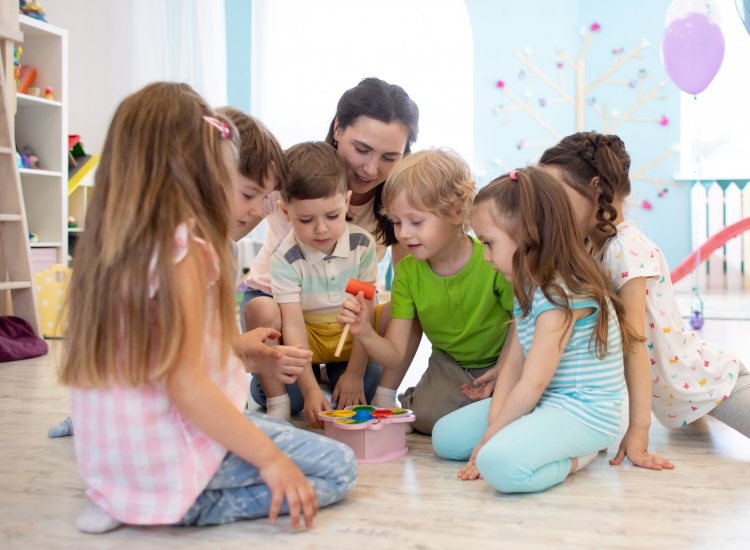Spelende kinderen met begeleider in kinderopvang