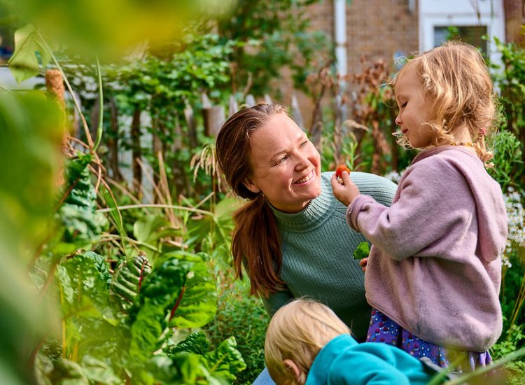 Pedagogisch medewerker kijkt lachend naar peuter