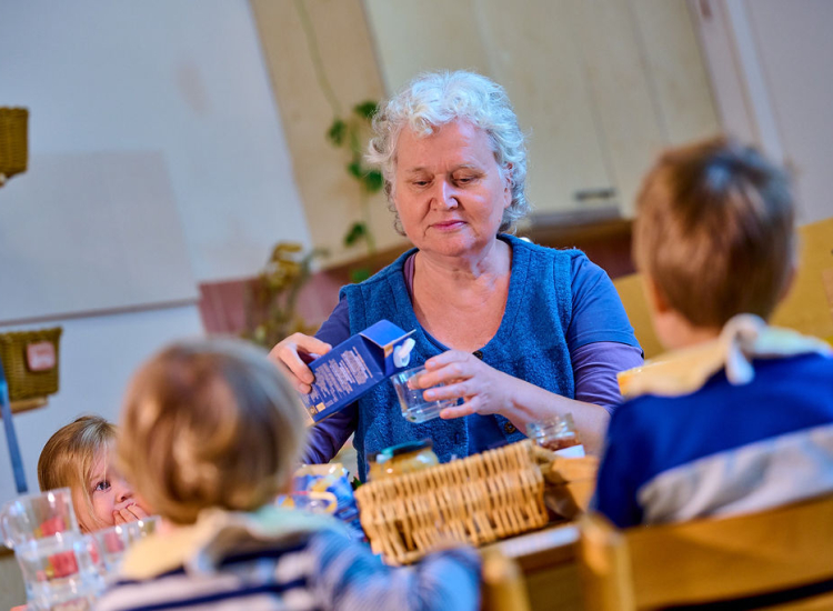 Groepsbegeleider schenkt glas melk in voor kinderen