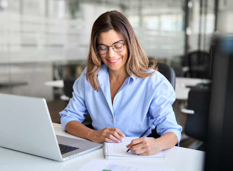 Vrouw volgt een training op haar laptop en maakt aantekeningen