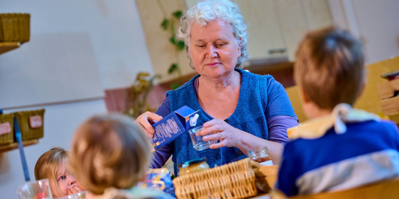 Groepsbegeleider schenkt glas melk in voor kinderen